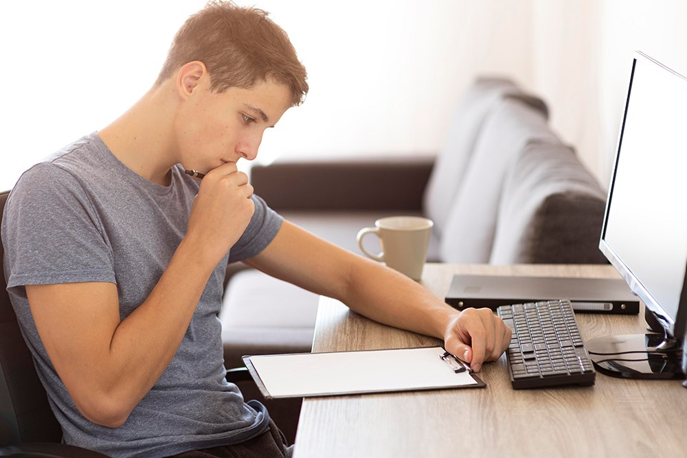 Homem jovem estudando em casa para fazer o ENEM Digital.