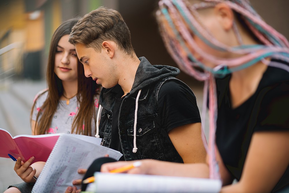 Alunos do ensino médio com diferentes características físicas e gêneros estudando juntos no intervalo.