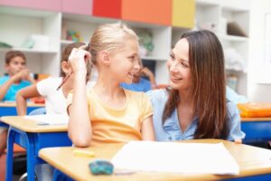 professora e aluna conversando em um ambiente escolar inclusivo.