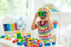 criança brincando com blocos coloridos em sala de aula.