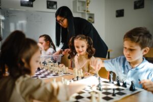 crianças jogando xadrez com orientação da professora.